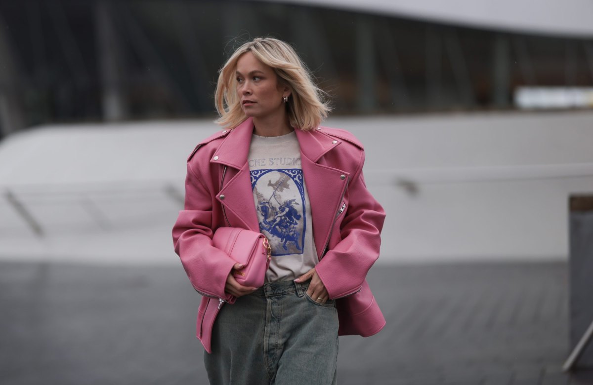MUNICH, GERMANY - MARCH 06: Nadine Berneis seen wearing The Frankie Shop pink oversized leather jacket, Acne Studios off-white / blue print pattern graphic cotton t-shirt, Acne Studios light blue / grey denim wide leg jeans / pans and Jacquemus pink leather Bambimou bag, on March 06, 2024 in Munich, Germany. (Photo by Jeremy Moeller/Getty Images)