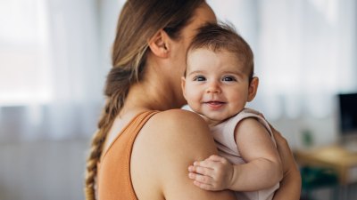 Portrait of a cute smiling baby girl looking directly at the camera while enjoying being in her mother's arms