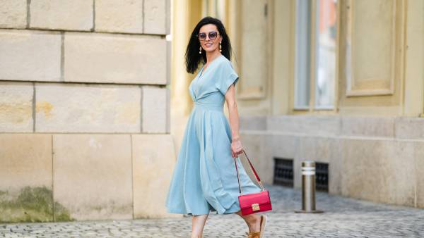 SIBIU, ROMANIA - JULY 27: Cosmina Pasarin wears sunglasses, a pastel blue gathered low-neck midi dress, a red bag, brown sandals with platform beige wicker platforms, on July 27, 2021 in Sibiu, Romania. (Photo by Edward Berthelot/Getty Images)