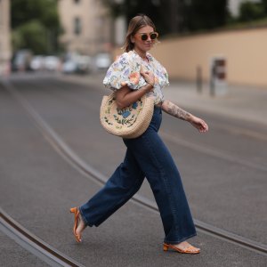 Aline Kaplan wearing Baum & Pferdgarten wide leg blue denim pants, & other stories white flower pattern cropped blouse and orange summer heels and Mango orange black shades on June 06, 2023 in Berlin, Germany.