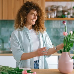 Happy woman enjoying while decorating her home with flowers.