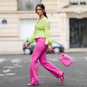 PARIS, FRANCE - AUGUST 12: Ketevan Giorgadze @katie.one wears neon pink high-waisted wide leg denim jeans from Zara, a neon green ruffle embroidered low-neck v-neck blouse with puff sleeves from Botrois, hot pink mules shoes from Zara, a hot pink knit bucket bag with stones from Manoush, on August 12, 2021 in Paris, France. (Photo by Edward Berthelot/Getty Images)