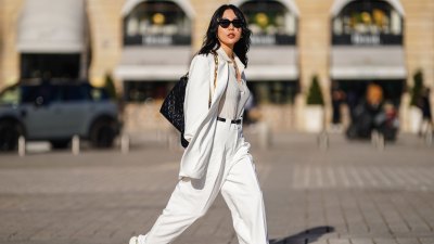 PARIS, FRANCE - FEBRUARY 27: Xiayan wears black Bottega Veneta sunglasses, silver earrings, a silver chain necklace, a white V-neck silk gown, a white long oversized Sundarbay blazer jacket with white suit Sundarbay matching pants, a black shiny leather belt, white and beige with gold details Stellaluna sneakers, a black shiny leather Louis Vuitton monogram-embossed Coussin PM crossbody bag, on February 27, 2021 in Paris, France. (Photo by Edward Berthelot/Getty Images)
