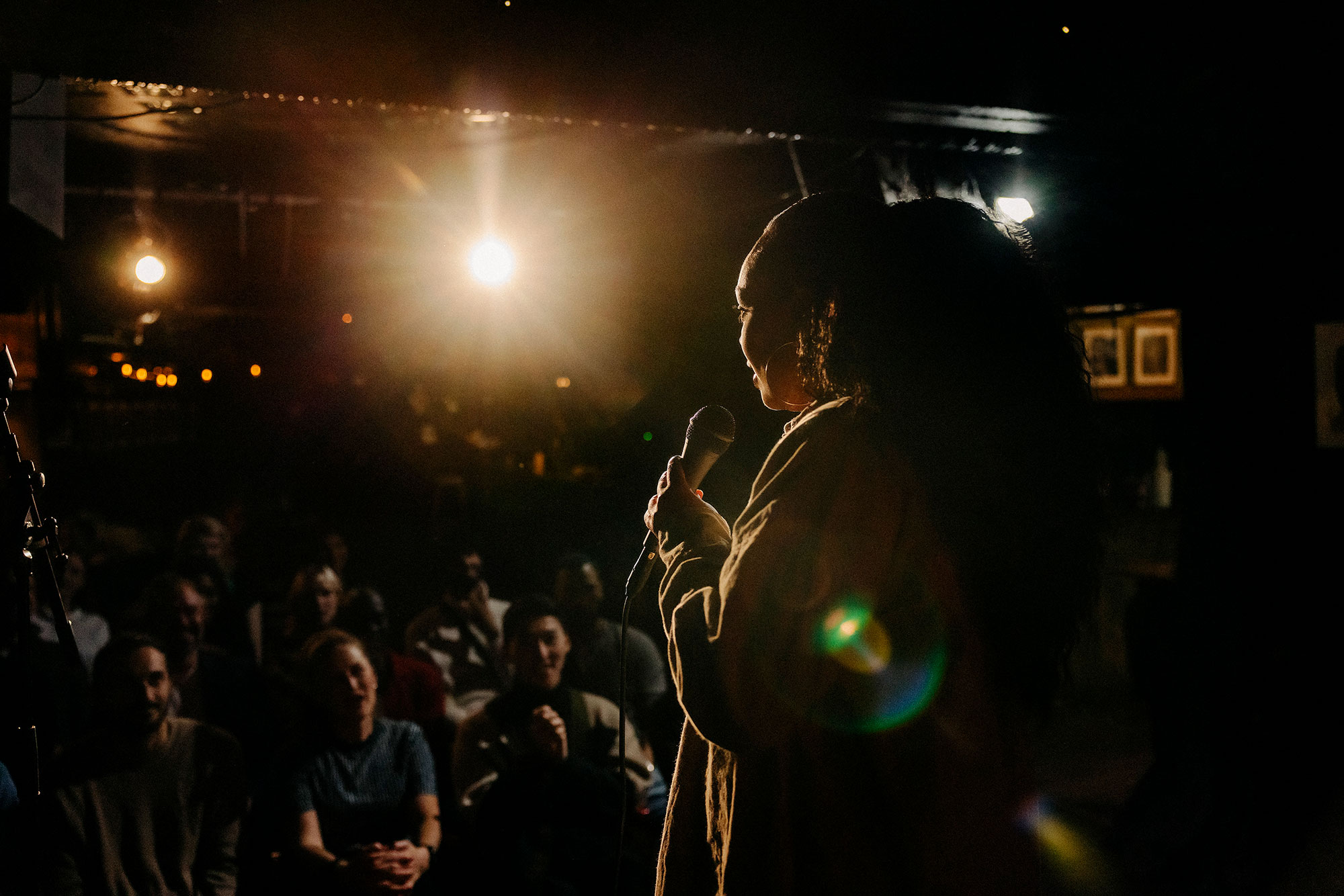 Young woman performing stand up comedy for multiracial audience