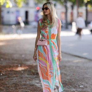 Mandy Bork seen wearing brown sunglasses from Tom Ford, a colorful buttoned / pleated / sleeveless long dress from Emilio Pucci, a pale pink Hermes Kelly mini bag and white creme sandals from Chanel, during Paris Fashion Week - Haute Couture Fall Winter 2022 2023, on July 06, 2022 in Paris, France.
