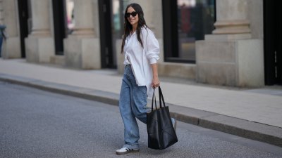 HAMBURG, GERMANY - SEPTEMBER 19: Jessica Schöne is seen wearing an oversized crisp white button-up shirt with a relaxed fit and rolled up sleeves, worn partially tucked into the front of her jeans; a white crew-neck T-shirt layered underneath; light blue straight-leg jeans with a loose, slightly slouchy silhouette; white low-top Adidas VL Court 3.0 sneakers with contrasting brown soles and black side stripes from Adidas; a large folded black leather Puzzle Tote shopper bag from Loewe; stacked gold and silver rings on her fingers; black acetate cat eye sunglasses; her long dark hair is worn down in soft natural waves on September 19, 2025 in Hamburg, Germany. (Photo by Moritz Scholz/Getty Images)