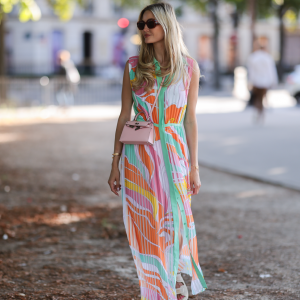 Mandy Bork seen wearing brown sunglasses from Tom Ford, a colorful buttoned / pleated / sleeveless long dress from Emilio Pucci, a pale pink Hermes Kelly mini bag and white creme sandals from Chanel, during Paris Fashion Week - Haute Couture Fall Winter 2022 2023, on July 06, 2022 in Paris, France.