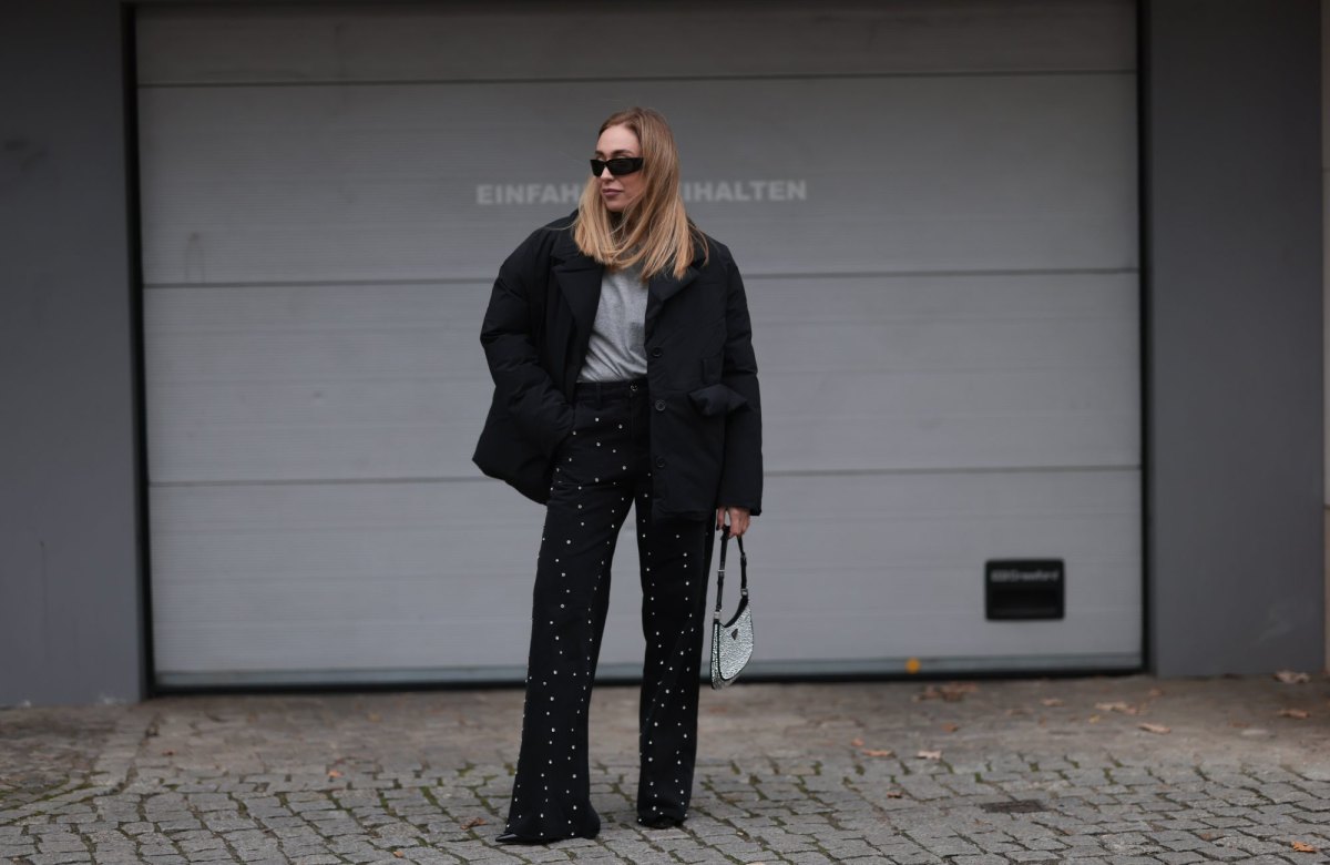 BERLIN, GERMANY - NOVEMBER 15: Sonia Lyson is seen wearing black rectangular sunglasses featuring wide temples with triangular logo embellishments from Prada; silver diamond-studded hoop earrings; a padded black jacket with notch lapels from Marina Hoermanseder x About You; underneath a grey t-shirt from Sézane; wide-legged straight black jeans with rhinestones pattern also from Marina Hoermanseder x About You; a crystal-embellished black leather “Cleo“ bag from Prada; and pointed black leather heels from Jimmy Choo on November 15, 2024 in Berlin, Germany. (Photo by Jeremy Moeller/Getty Images)
