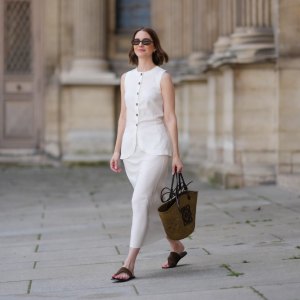PARIS, FRANCE - MAY 25: Marissa Cox wears a white Arket linen skirt set, a sleeveless long top with buttons, a brown raffia Loewe basket bag, ATP Atelier brown suede sandals / shoes, Jimmy Fairly x Reformation sunglasses, during a street style fashion photo session, on May 25, 2024 in Paris, France. (Photo by Edward Berthelot/Getty Images)