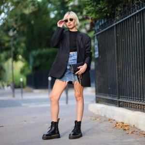 PARIS, FRANCE - AUGUST 25: Emy venturini wears black vintage RayBan sunglasses, gold large earrings, a gold chain necklace, a black halter-neck cropped t-shirt from Zara, a black oversized vintage blazer jacket from Prada, a gold chain bracelet, a gold ring, a black shiny grained leather WOC crossbody bag from Chanel, a blue faded high waist ripped short skirt from Levi's, black shiny leather laces ankle boots from Dr Martens, on August 25, 2021 in Paris, France. (Photo by Edward Berthelot/Getty Images)