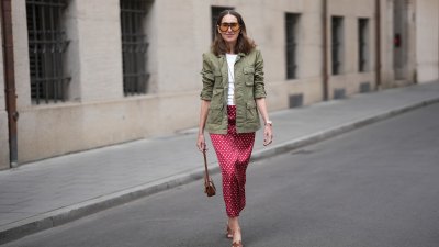 MUNICH, GERMANY - APRIL 28: Annette Weber is seen wearing an olive green cotton field jacket with a relaxed fit, button front closure and multiple flap patch pockets from AG Jeans; a white cotton crew neck top with a fitted silhouette from Brunello Cucinelli; a red satin longuette skirt with a straight silhouette and white polka dot print from Glamometer x Seidensticker; brown calfskin "Oasis” sandals with an open toe, low block heel and cut out strap detail from Hermès; a natural pedicure visible; a structured Celine Tabou shoulder bag, characterized by a flap design with a distinctive golden padlock "Celine Paris" that recalls the Celine 16 line, made of calfskin; a long gold chain necklace with a tassel pendant from Manuela Fumagalli; multiple gold rings; dark nail polish; oversized aviator acetate sunglasses with orange tinted lenses from Bottega Veneta; a Rolex Day-Date 36 Everose rose gold with Oyster bracelet; her medium brown hair is worn loose in soft waves with a center part; with natural make up on April 28, 2026 in Munich, Germany. (Photo by Moritz Scholz/Getty Images)