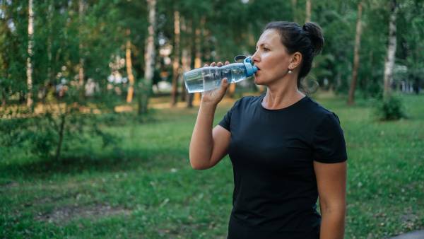 woman drinking water from a bottle at training in the park outdoor