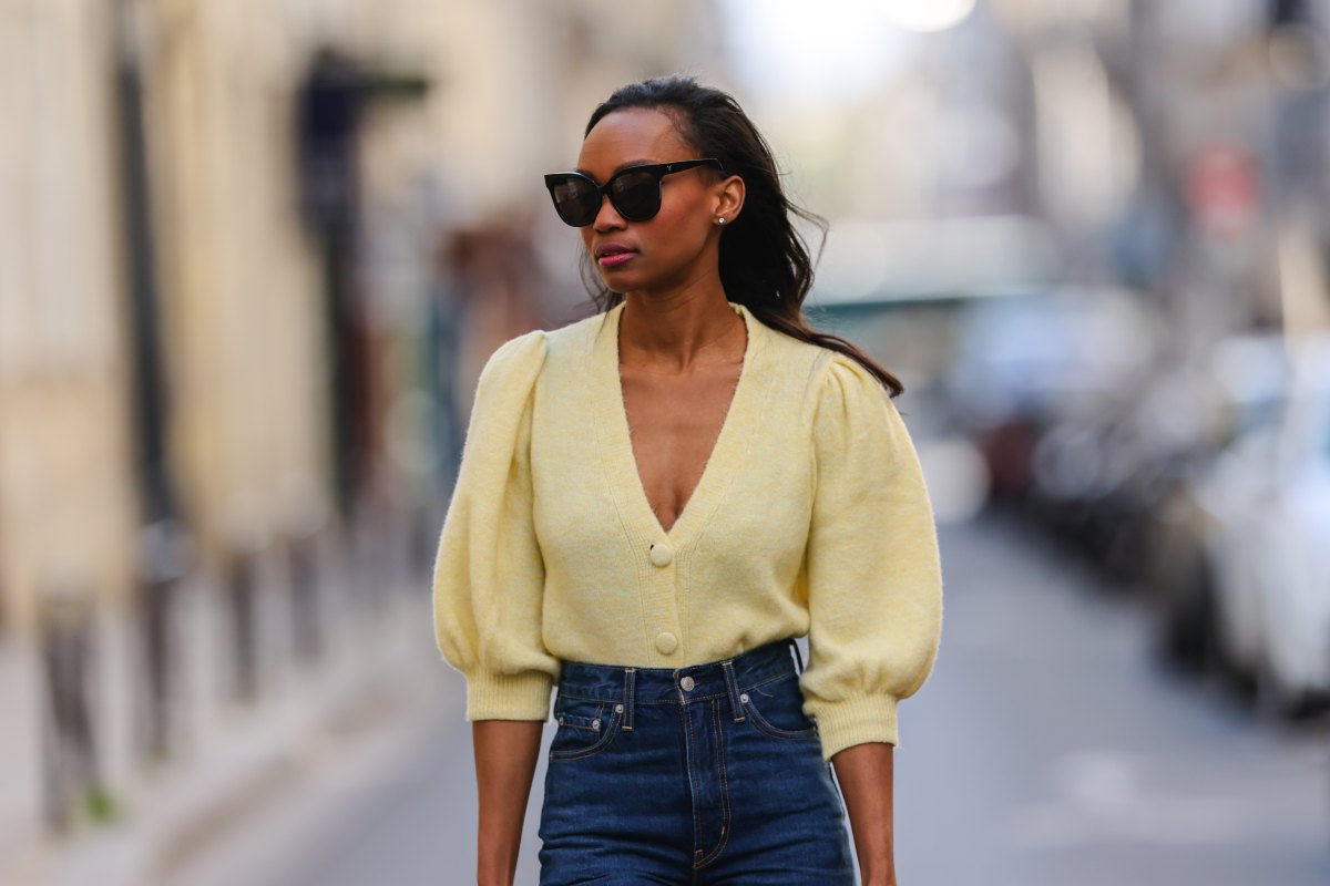 PARIS, FRANCE - APRIL 03: Emilie Joseph @in_fashionwetrust wears sunglasses, pale pastel yellow a puffed sleeves wool cardigan from Mango, high rise blue denim jeans pants from Levi's, on April 03, 2021 in Paris, France. (Photo by Edward Berthelot/Getty Images)