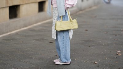 FRANKFURT AM MAIN, GERMANY - MARCH 26: Julia Kammerer is seen wearing a light pink silk shirt with a pointed collar and a partial button placket from Lily Silk; a baby blue knit sweater draped around her shoulders from ASOS; light blue wide leg denim jeans with a relaxed fit from Levi's; a white floral lace wrap skirt overlay featuring delicate scalloped edges from NA-KD; light pink and white leather "Speedcat Ballet Sneaker" with a thin rubber sole from Puma; a light green leather "L Looong" handbag with a horizontal silhouette and dual top handles from Longchamp; her jewelry includes chunky gold hoop earrings and gold tone stacked rings worn across multiple fingers from H&M, Pandora and My Jewellery; orange tinted aviator sunglasses with a thin black frame from Bershka; her blonde hair is styled in loose waves with a center part on March 26, 2026 in Frankfurt am Main, Germany. (Photo by Moritz Scholz/Getty Images)