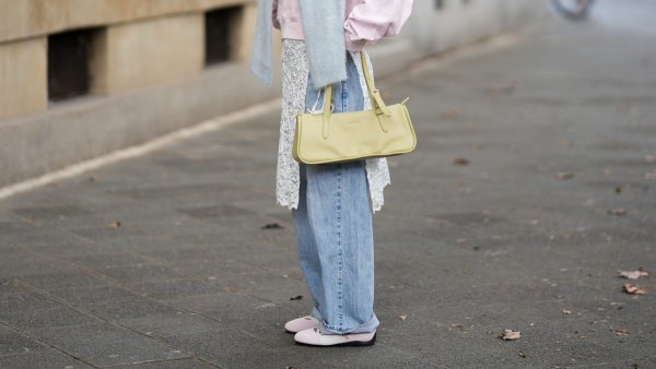 FRANKFURT AM MAIN, GERMANY - MARCH 26: Julia Kammerer is seen wearing a light pink silk shirt with a pointed collar and a partial button placket from Lily Silk; a baby blue knit sweater draped around her shoulders from ASOS; light blue wide leg denim jeans with a relaxed fit from Levi's; a white floral lace wrap skirt overlay featuring delicate scalloped edges from NA-KD; light pink and white leather "Speedcat Ballet Sneaker" with a thin rubber sole from Puma; a light green leather "L Looong" handbag with a horizontal silhouette and dual top handles from Longchamp; her jewelry includes chunky gold hoop earrings and gold tone stacked rings worn across multiple fingers from H&M, Pandora and My Jewellery; orange tinted aviator sunglasses with a thin black frame from Bershka; her blonde hair is styled in loose waves with a center part on March 26, 2026 in Frankfurt am Main, Germany. (Photo by Moritz Scholz/Getty Images)