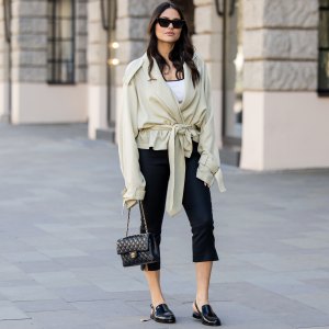 BERLIN, GERMANY - MARCH 23: Aylin Sengül wears black capri cropped pants Massimo Dutti, beige belted oversized trench jacket the Frankie Shop, black loafers & bag Chanel, sunglasses Phoebe Philo on March 23, 2026 in Berlin, Germany. (Photo by Christian Vierig/Getty Images)