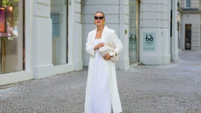 BERLIN, GERMANY - JULY 05: Tina Haase wears Gant white Maxi coat, Nakd white maxi dress, Arket mesh flats, Arket cream leather clutch bag, Joseph black Cateye Sunglasses on July 05, 2025 in Berlin, Germany. (Photo by Christian Vierig/Getty Images)