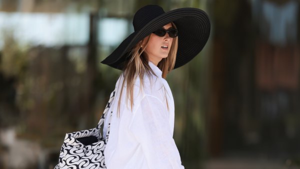 COPENHAGEN, DENMARK - AUGUST 06: A fashion week guest is seen wearing a white long-sleeved shirt, a white oversized shirt with wide sleeves and white shorts, an oversized black hat, an oversized patterned bag with white and black graphics and black sandals before OperaSport show during day two of the Copenhagen Fashion Week (CPHFW) SS25 on August 06, 2024 in Copenhagen, Denmark. (Photo by Jeremy Moeller/Getty Images)