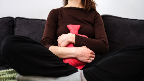 Getty Images 1247581156 - Woman with a heating pad on her abdomen