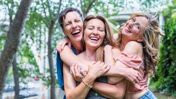 Close up of three cheerful mature female friends hugging together. Middle aged friends sharing time together and having fun.