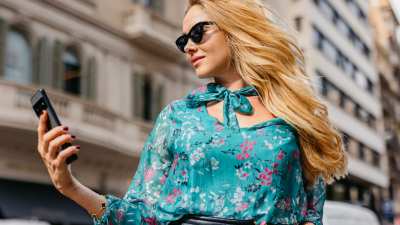 Beautiful blonde mature woman using her smart phone on the street in Barcelona in Spain.