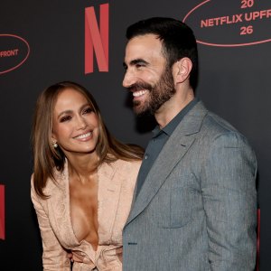 Jennifer Lopez and Brett Goldstein smiling together on a red carpet.
