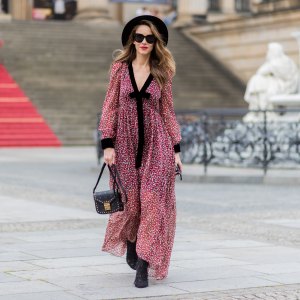 Alexandra Lapp wearing Boho Style, a red and cream floral print maxi dress from Philosophy di Lorenzo Serafini in sheer silk chiffon and bold black trims with a ribbon tie, Toubootfrou ankle boots with rete, organze and suede in black from Christian Louboutin, Celine Audrey sunglasses in black, Maison Maison Michel hat Virginie fedora, MCM Patricia Shoulder Bag in a vintage shape during the Mercedes-Benz Fashion Week Berlin Spring/Summer 2018 on July 7, 2017 in Berlin, Germany.