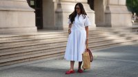 FRANKFURT AM MAIN, GERMANY - JULY 10: Angelika Hanel is seen wearing a white short-sleeved shirt midi dress with a flared silhouette and soft pleating from Erika Cavallini; a pair of signature Alaïa ballet flats in red fishnet textile and patent leather, a buckle strap on top and round toes from Alaïa; the ICARE maxi shopper crafted from hand-embroidered natural raffia and a brown gold oversized, sculptured Cassandre from Saint Laurent adorned with a red and white silk bandana from Arket tied to the handle; a silver Rolex Daytona watch; a silver diamond ring; a yellow golden Juste un Clou bracelet from Cartier; a pavé diamond Tennis bracelet; a bold sterling silver Bone Cuff from Tiffany & Co.; oversized black aviator sunglasses with orange shaded glasses from Kapten & Son; long brown hair and natural make-up on July 10, 2025 in Frankfurt am Main, Germany. (Photo by Moritz Scholz/Getty Images)