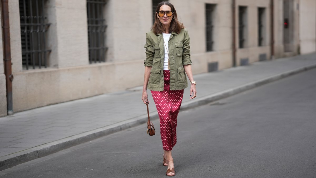MUNICH, GERMANY - APRIL 28: Annette Weber is seen wearing an olive green cotton field jacket with a relaxed fit, button front closure and multiple flap patch pockets from AG Jeans; a white cotton crew neck top with a fitted silhouette from Brunello Cucinelli; a red satin longuette skirt with a straight silhouette and white polka dot print from Glamometer x Seidensticker; brown calfskin "Oasis” sandals with an open toe, low block heel and cut out strap detail from Hermès; a natural pedicure visible; a structured Celine Tabou shoulder bag, characterized by a flap design with a distinctive golden padlock "Celine Paris" that recalls the Celine 16 line, made of calfskin; a long gold chain necklace with a tassel pendant from Manuela Fumagalli; multiple gold rings; dark nail polish; oversized aviator acetate sunglasses with orange tinted lenses from Bottega Veneta; a Rolex Day-Date 36 Everose rose gold with Oyster bracelet; her medium brown hair is worn loose in soft waves with a center part; with natural make up on April 28, 2026 in Munich, Germany. (Photo by Moritz Scholz/Getty Images)