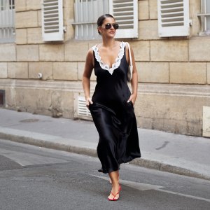 Gili Biegun wears a black silk midi dress with white lace detailing by Maria McManus, cream-white leather shoulder bag, red kitten-heel flip-flops, and diamond earrings during Day One of Paris Fashion Week - Haute Couture Fall/Winter 2026/2027 on July 06, 2026 in Paris, France.