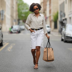 PARIS, FRANCE - MAY 08: Ellie Delphine wears a full Mango look, sunglasses, golden earrings, a white linen shirt, a black leather belt with golden buckle, golden bracelets, a white ripped denim shorts, a large brown raffia bag, black sandals, during a street style fashion photo session, on May 08, 2024 in Paris, France. (Photo by Edward Berthelot/Getty Images)