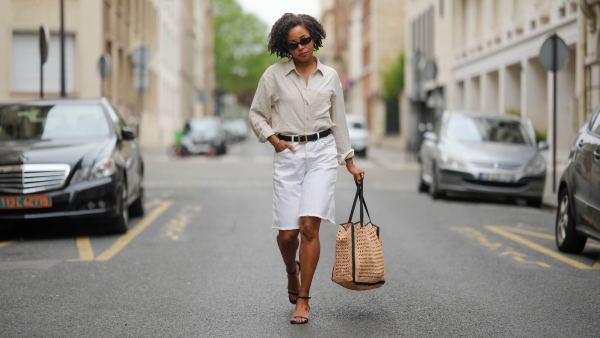 PARIS, FRANCE - MAY 08: Ellie Delphine wears a full Mango look, sunglasses, golden earrings, a white linen shirt, a black leather belt with golden buckle, golden bracelets, a white ripped denim shorts, a large brown raffia bag, black sandals, during a street style fashion photo session, on May 08, 2024 in Paris, France. (Photo by Edward Berthelot/Getty Images)