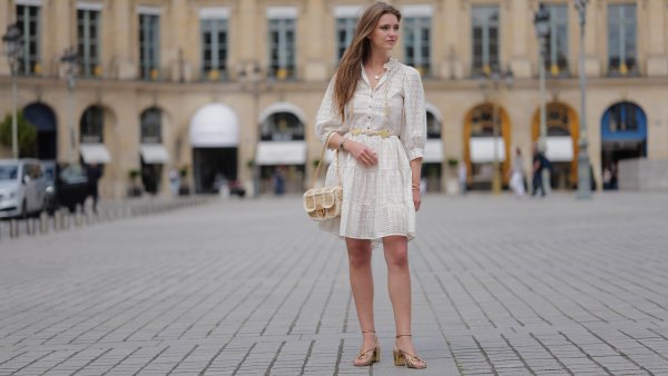 PARIS, FRANCE - JUNE 14: Segolene Hyppolite wears sunglasses, a white mini pleated and gathered summer dress with floral embroidery and long sleeves from Anne Fontaine, a rope belt from Anne Fontaine, a raffia bag from Vanessa Bruno, golden sandals / shoes from Sezane, during a street style fashion photo session, on June 14, 2024 in Paris, France. (Photo by Edward Berthelot/Getty Images)