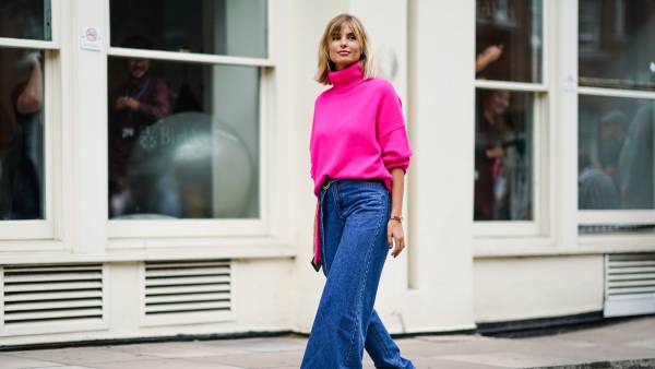 LONDON, ENGLAND - SEPTEMBER 16: Xenia Adonts wears a neon pink turtleneck wool pullover, blue denim jeans pants with one flare leg, gray platform boots, during London Fashion Week September 2019 on September 16, 2019 in London, England. (Photo by Edward Berthelot/Getty Images)