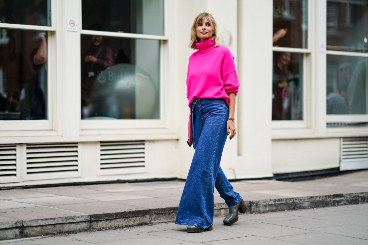 LONDON, ENGLAND - SEPTEMBER 16: Xenia Adonts wears a neon pink turtleneck wool pullover, blue denim jeans pants with one flare leg, gray platform boots, during London Fashion Week September 2019 on September 16, 2019 in London, England. (Photo by Edward Berthelot/Getty Images)