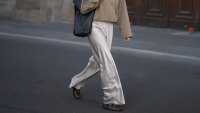 BERLIN, GERMANY - AUGUST 30: Aylin Sengül is seen wearing a beige cropped trench coat from COS; cream satin wide leg trousers from Almada Label; black mesh ballet flats from Alaïa; a large black leather tote Trullo bag from COS; silver rings; black cat eye sunglasses with dark tinted lenses from Phoebe Philo; dark brown hair worn in a sleek ponytail on August 30, 2026 in Berlin, Germany. (Photo by Moritz Scholz/Getty Images)