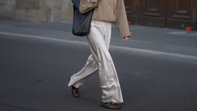 BERLIN, GERMANY - AUGUST 30: Aylin Sengül is seen wearing a beige cropped trench coat from COS; cream satin wide leg trousers from Almada Label; black mesh ballet flats from Alaïa; a large black leather tote Trullo bag from COS; silver rings; black cat eye sunglasses with dark tinted lenses from Phoebe Philo; dark brown hair worn in a sleek ponytail on August 30, 2026 in Berlin, Germany. (Photo by Moritz Scholz/Getty Images)