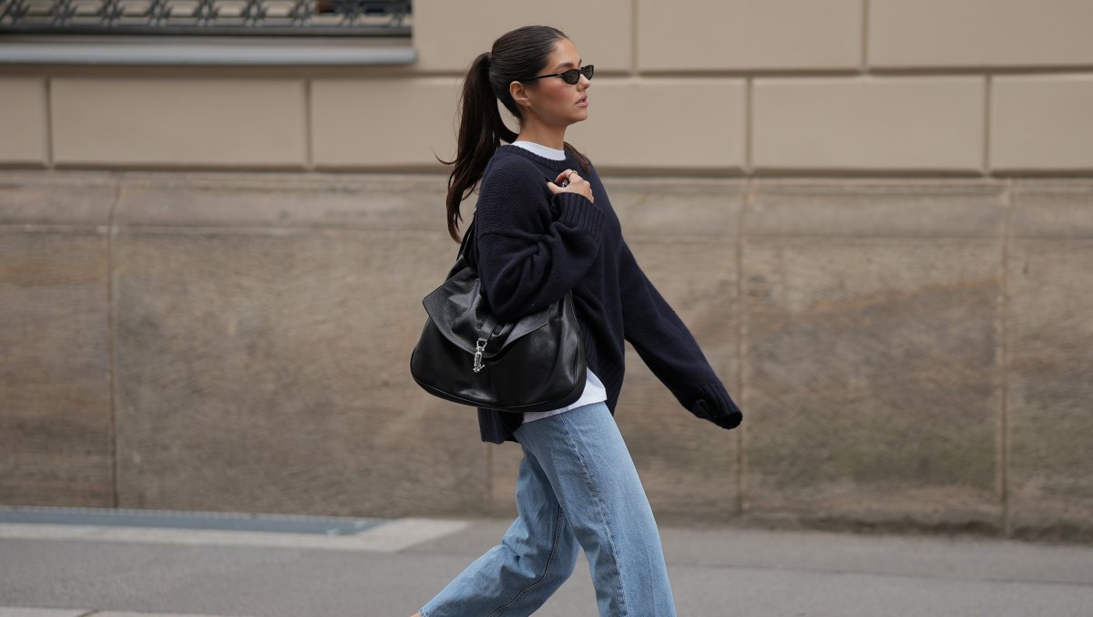 BERLIN, GERMANY - JULY 23: Aylin Sengül is seen wearing an oversized navy knit sweater from COS layered over a white crew neck T-shirt from Arket; light blue straight leg jeans from COS; black leather slingback loafers with CC logo hardware from Chanel; a black Jackie 1961 shoulder bag crafted from soft grained leather with a signature silver tone piston clasp from Gucci; black narrow rectangular sunglasses from Miu Miu on July 23, 2026 in Berlin, Germany. (Photo by Moritz Scholz/Getty Images)