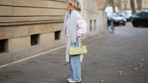 FRANKFURT AM MAIN, GERMANY - MARCH 26: Julia Kammerer is seen wearing a light pink silk shirt with a pointed collar and a partial button placket from Lily Silk; a baby blue knit sweater draped around her shoulders from ASOS; light blue wide leg denim jeans with a relaxed fit from Levi's; a white floral lace wrap skirt overlay featuring delicate scalloped edges from NA-KD; light pink and white leather "Speedcat Ballet Sneaker" with a thin rubber sole from Puma; a light green leather "L Looong" handbag with a horizontal silhouette and dual top handles from Longchamp; her jewelry includes chunky gold hoop earrings and gold tone stacked rings worn across multiple fingers from H&M, Pandora and My Jewellery; orange tinted aviator sunglasses with a thin black frame from Bershka; her blonde hair is styled in loose waves with a center part on March 26, 2026 in Frankfurt am Main, Germany. (Photo by Moritz Scholz/Getty Images)