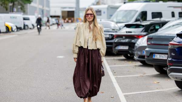 COPENHAGEN, DENMARK - AUGUST 06: A guest wears wide leg burgundy skirt, beige jacket, Miu Miu bag, sunglasses outside MKDT Studio during Copenhagen Fashion Week day three on August 06, 2025 in Copenhagen, Denmark. (Photo by Christian Vierig/Getty Images)