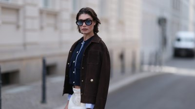 BERLIN, GERMANY - JUNE 08: Sarah Posch seen wearing a Sandro look, a cropped navy top layered under a dark brown jacket, paired with white wide leg trousers, black Soera ballerinas, a creme Coach bag, and sunglasses by A. Kjaerbede on June 08, 2026 in Berlin, Germany. (Photo by Jeremy Moeller/Getty Images)
