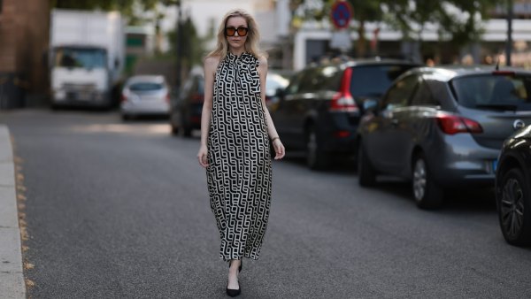 BERLIN, GERMANY - JUNE 19: Lil Paulin is seen wearing oversized black square-framed sunglasses with orange lenses and wide temples, gold hoop earrings, a flowy sleeveless maxi dress with a halter neck and a geometric black and white pattern, a gold rectangular watch from Daniel Wellington, several filigree silver rings, and pointed black suede slingback kitten heels on June 19, 2025 in Berlin, Germany. (Photo by Jeremy Moeller/Getty Images)