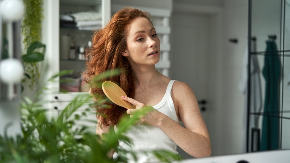 Redhead woman brushing hair in the bathroom