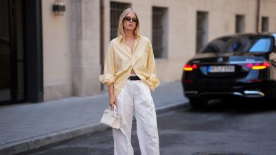 MUNICH, GERMANY - JULY 27: Lea Rohe is seen wearing a pale yellow oversized vintage cotton button front shirt; white wide leg linen trousers from Mango x Hailey Bieber; a black leather belt from The Horse; dark brown leather boat shoes with metal toggles from Longchamp; a small white structured leather top handle bag with silver tone hardware from Le Tanneur; rectangular black acetate sunglasses with dark tinted lenses from Corlin Eyewear on July 27, 2026 in Munich, Germany. (Photo by Moritz Scholz/Getty Images)