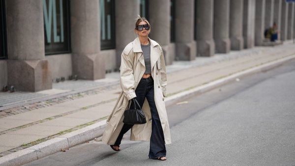 COPENHAGEN, DENMARK - AUGUST 3: Sophia Geiss is seen wearing a beige oversized double breasted cotton trench coat with wide lapels, epaulettes, storm flap, adjustable cuff straps and a self tie belt from H&M; a grey fitted crewneck T shirt from Brandy Melville; dark indigo wide leg jeans from Acne Studios; black leather minimalist open toe flat sandals from Mango; a black leather structured top handle tote bag from COS; oversized black shield sunglasses with a bold acetate frame from Tom Ford during the Copenhagen Fashion Week Spring/Summer 2027 on August 3, 2026 in Copenhagen, Denmark. (Photo by Moritz Scholz/Getty Images)