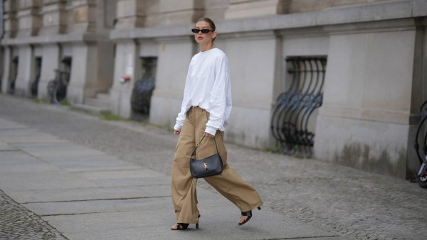 BERLIN, GERMANY - JULY 23: Sophia Geiss is seen wearing an oversized white crew neck sweatshirt from Black Palms; beige oversized wide leg cargo trousers with utility patch pockets from The Frankie Shop; black leather thong sandals from Mango; a black smooth leather Saint Laurent Le 5 à 7 Hobo shoulder bag with the signature gold tone YSL hook closure; black narrow oval frame sunglasses from Saint Laurent; silver hoop earrings on July 23, 2026 in Berlin, Germany. (Photo by Moritz Scholz/Getty Images)