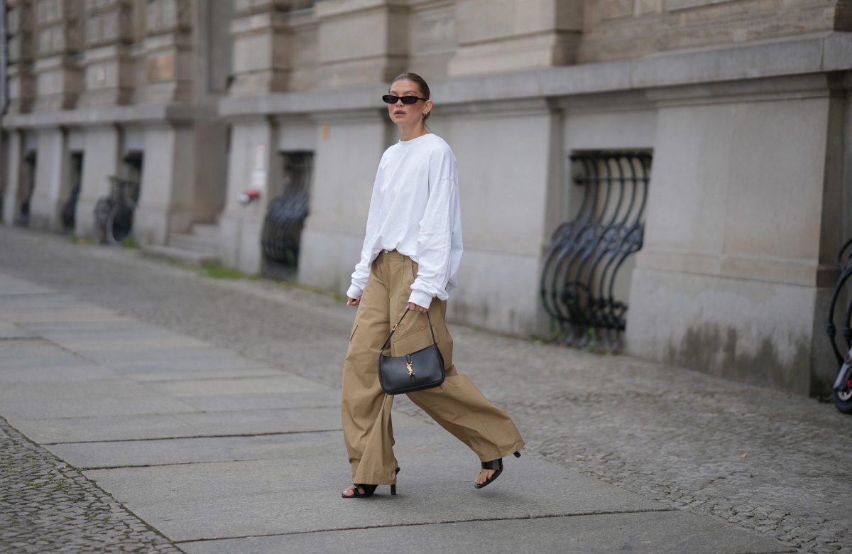 BERLIN, GERMANY - JULY 23: Sophia Geiss is seen wearing an oversized white crew neck sweatshirt from Black Palms; beige oversized wide leg cargo trousers with utility patch pockets from The Frankie Shop; black leather thong sandals from Mango; a black smooth leather Saint Laurent Le 5 à 7 Hobo shoulder bag with the signature gold tone YSL hook closure; black narrow oval frame sunglasses from Saint Laurent; silver hoop earrings on July 23, 2026 in Berlin, Germany. (Photo by Moritz Scholz/Getty Images)