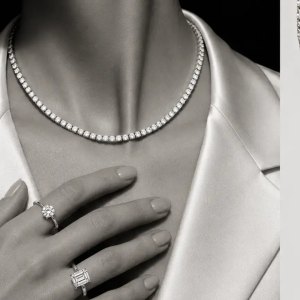 View of a woman wearing everyday diamond jewelry, including a tennis necklace and statement rings