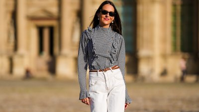 Alba Garavito Torre wears white pearl earrings, a gingham checkered black and white shirt with Long Sleeve Ruffles from Serendipia, Mom jeans in white from Maison 123 Paris, a brown thin leather belt, on October 10, 2021 in Paris, France.