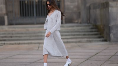 Jill Asemota seen wearing black vintage sunglasses, Dorothee Schumacher grey wool knit long dress, matching Dorothee Schumacher grey wool knit cardigan jacket, white cotton socks, Adidas white leather Samba sneakers, on November 04, 2023 in Berlin, Germany.